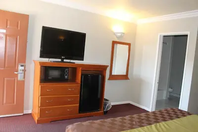 a bedroom with a flat screen tv on a dresser at West Coast Inn Santa Ana in Santa Ana