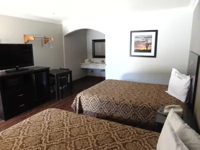 a hotel room with two beds and a flat screen tv at West Coast Inn Santa Ana in Santa Ana