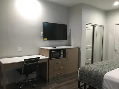 a bedroom with a desk with a television and a bed at Cali Inn in Carson
