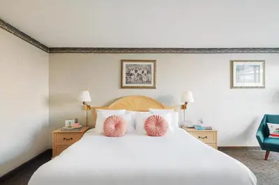 a bedroom with a large white bed with pink pillows at Glendale Express Hotel Los Angeles in Glendale