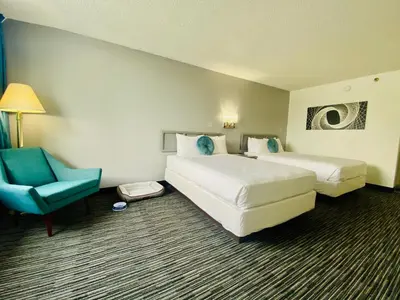 a hotel room with two beds and a blue chair at Glendale Express Hotel Los Angeles in Glendale