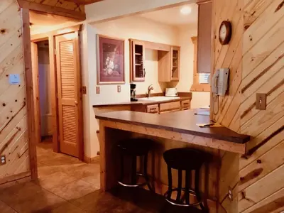 a kitchen with a counter and two bar stools at Giant Oaks Lodge in Running Springs