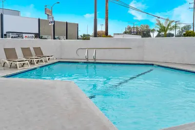 a swimming pool with two chairs and a building at Motel 6-El Monte, CA - Los Angeles in El Monte