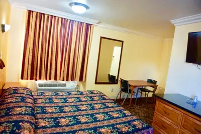 a hotel room with a bed and a desk and a mirror at Satellite Motel, Los Angeles - LAX in South Los Angeles