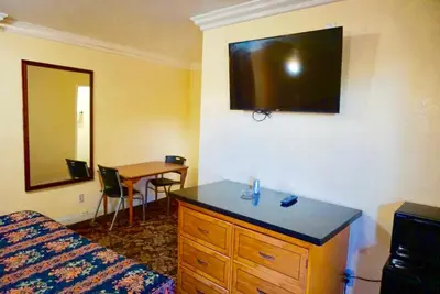 a hotel room with a bed and a dresser with a mirror at Satellite Motel, Los Angeles - LAX in South Los Angeles