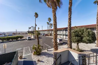 a parking lot with palm trees and a building at Economy Inn Barstow in Barstow
