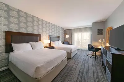 a hotel room with two beds and a desk and a television at Jamaica Bay Inn Marina Del Rey Tapestry Collection by Hilton in Los Angeles