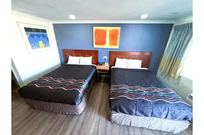 a hotel room with two beds and a desk at Hotel Ridgecrest An Extended Stay Studio in Ridgecrest