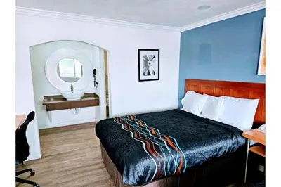 a hotel room with a bed and a desk and a mirror at Hotel Ridgecrest An Extended Stay Studio in Ridgecrest