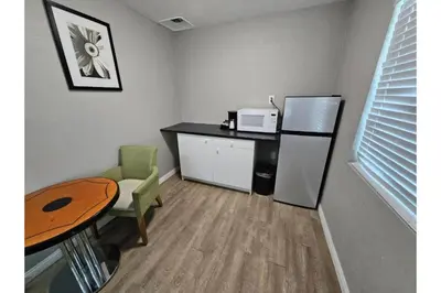 a kitchen with a desk and a refrigerator and a table at Hotel Ridgecrest An Extended Stay Studio in Ridgecrest