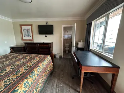 a bedroom with a bed and a desk and a television at Flamingo Motel Oxnard in Oxnard