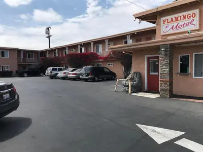 a parking lot with cars parked in front of a building at Flamingo Motel Oxnard in Oxnard