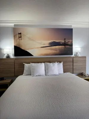 a bedroom with a bed with a painting on the wall at Days Inn by Wyndham Near City Of Hope in Duarte