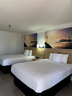 a hotel room with two beds and a painting on the wall at Days Inn by Wyndham Near City Of Hope in Duarte