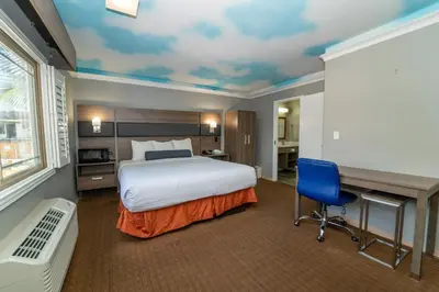 a hotel room with a bed and a desk and a bed at Hollywood Palms Inns & Suites in Los Angeles