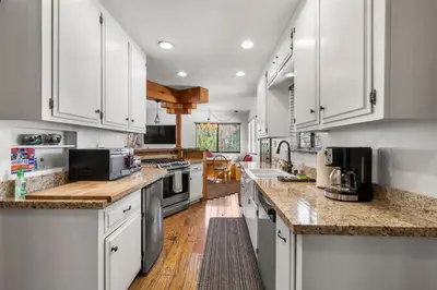 a kitchen with white cabinets and marble counter tops at Piece of Paradise in Big Bear Lake