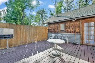 a wooden deck with a table and chairs on it at Lodge House-Family Cabin with Pool Table by Big Bear Vacations in Big Bear Lake