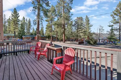 three red chairs and a table on a deck at Lodge House-Family Cabin with Pool Table by Big Bear Vacations in Big Bear Lake