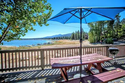 a picnic table with an umbrella next to a fence at Sunrise Lakefront Family Cabin by Big Bear Vacations in Big Bear Lake