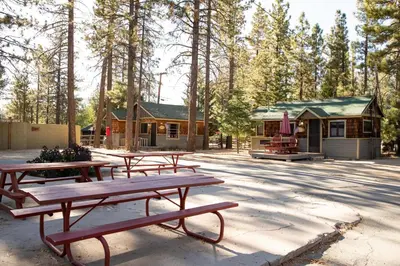 a group of picnic tables in front of a cabin at Sunrise Lakefront Family Cabin by Big Bear Vacations in Big Bear Lake
