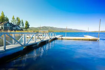 a dock on a lake with a house in the background at Twin Pines Family Cabin by Big Bear Vacations in Big Bear Lake