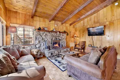 a living room with couches and a stone fireplace at Casa Catalina-667 by Big Bear Vacations in Big Bear Lake