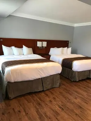 two beds sitting in a hotel room with wood floors at Rex Motel in Ventura