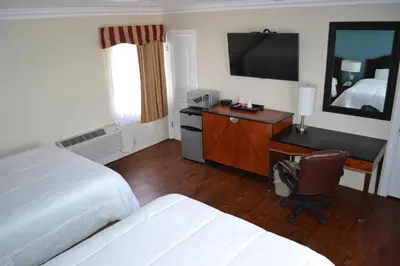 a hotel room with two beds and a desk with a television at Rex Motel in Ventura