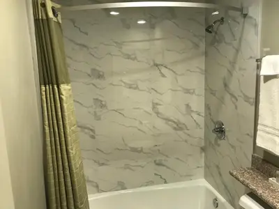 a bathroom with a shower and a tub and a sink at Hyland Inn Brea in Brea
