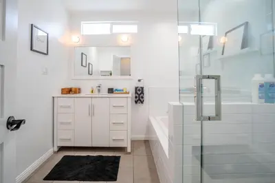 a white bathroom with a shower and a sink at Enchanting Sherman Oaks Home With Pool permit #HSR two five zero zero 3222 in Sherman Oaks