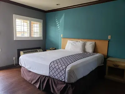 a bedroom with a large bed with a blue wall at Eagle Inn Motel in Long Beach