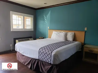 a bedroom with a large bed with a blue wall at Eagle Inn Motel in Long Beach