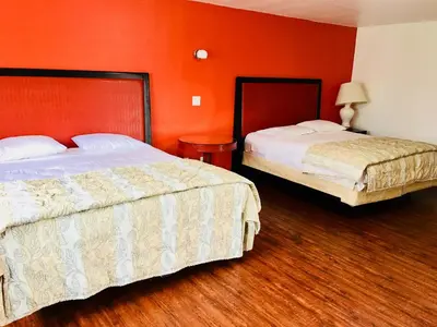 two beds in a hotel room with orange walls at norwalk inn & suites in Norwalk