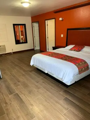 a bedroom with a large bed and a wooden floor at norwalk inn & suites in Norwalk