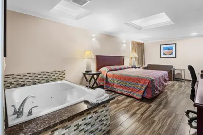 a hotel room with a tub and a bed at Sky Palm Motel - Orange in Orange