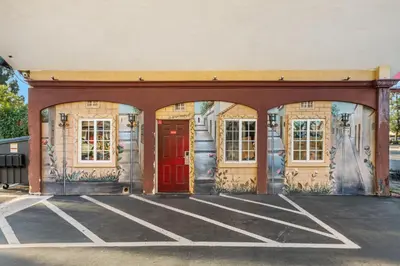 a building with a red door in a parking lot at Sky Palm Motel - Orange in Orange