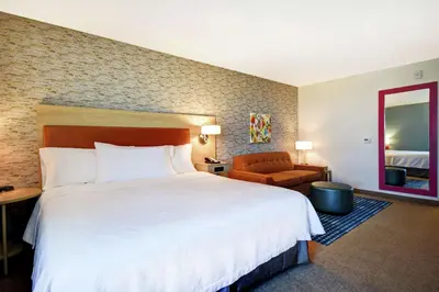 a hotel room with a large bed and a chair at Home2 Suites by Hilton Victorville in Victorville