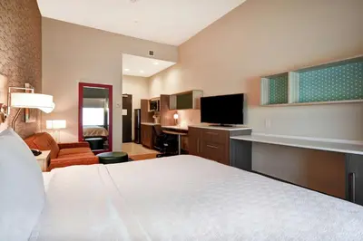 a hotel room with a bed and a living room at Home2 Suites by Hilton Victorville in Victorville