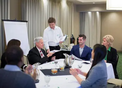 a group of people sitting around a table in a meeting at Holiday Inn & Suites - Barstow by IHG in Barstow