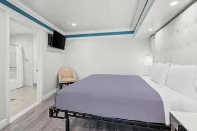 a bedroom with a large bed and a chair at Rodeway Inn Commerce - Los Angeles in Commerce