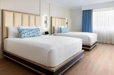 two beds in a hotel room with blue curtains at The Anza-a Calabasas Hotel in Calabasas