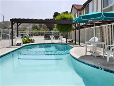 a large swimming pool with chairs and an umbrella at Super 8 by Wyndham Santa Clarita/Valencia in Santa Clarita