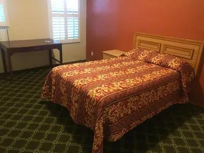 a bedroom with a bed and a table and a window at Hotel West Inn, Hollywood - LA in Los Angeles