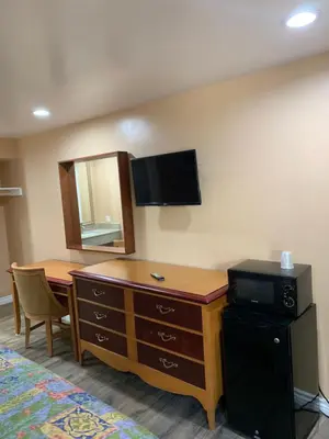 a room with a dresser with a mirror and a television at Budget Inn Motel in San Gabriel