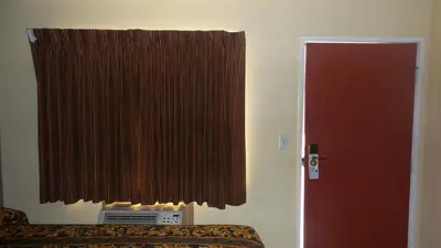 a room with a bed and a window with a curtain at Budget Inn Motel in San Gabriel