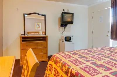 a bedroom with a bed and a dresser and a tv at Mission Motel in Lynwood
