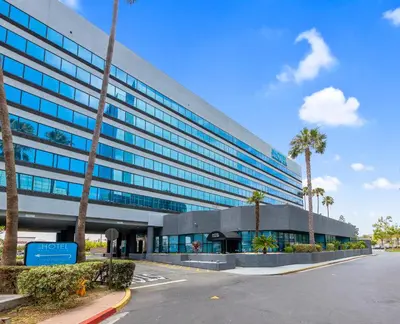 an office building with palm trees in front of it at Hotel Huntington Beach in Huntington Beach
