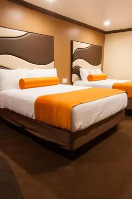two beds in a hotel room with orange sheets at Redondo Pier Inn in Redondo Beach