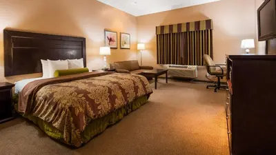 a hotel room with a large bed and a chair at Best Western Route 66 Glendora Inn in Glendora