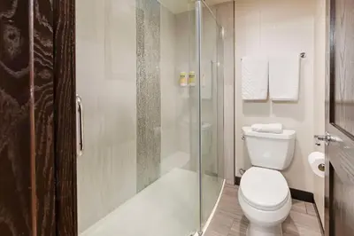 a bathroom with a toilet and a glass shower at Best Western Plus Redondo Beach Inn in Redondo Beach